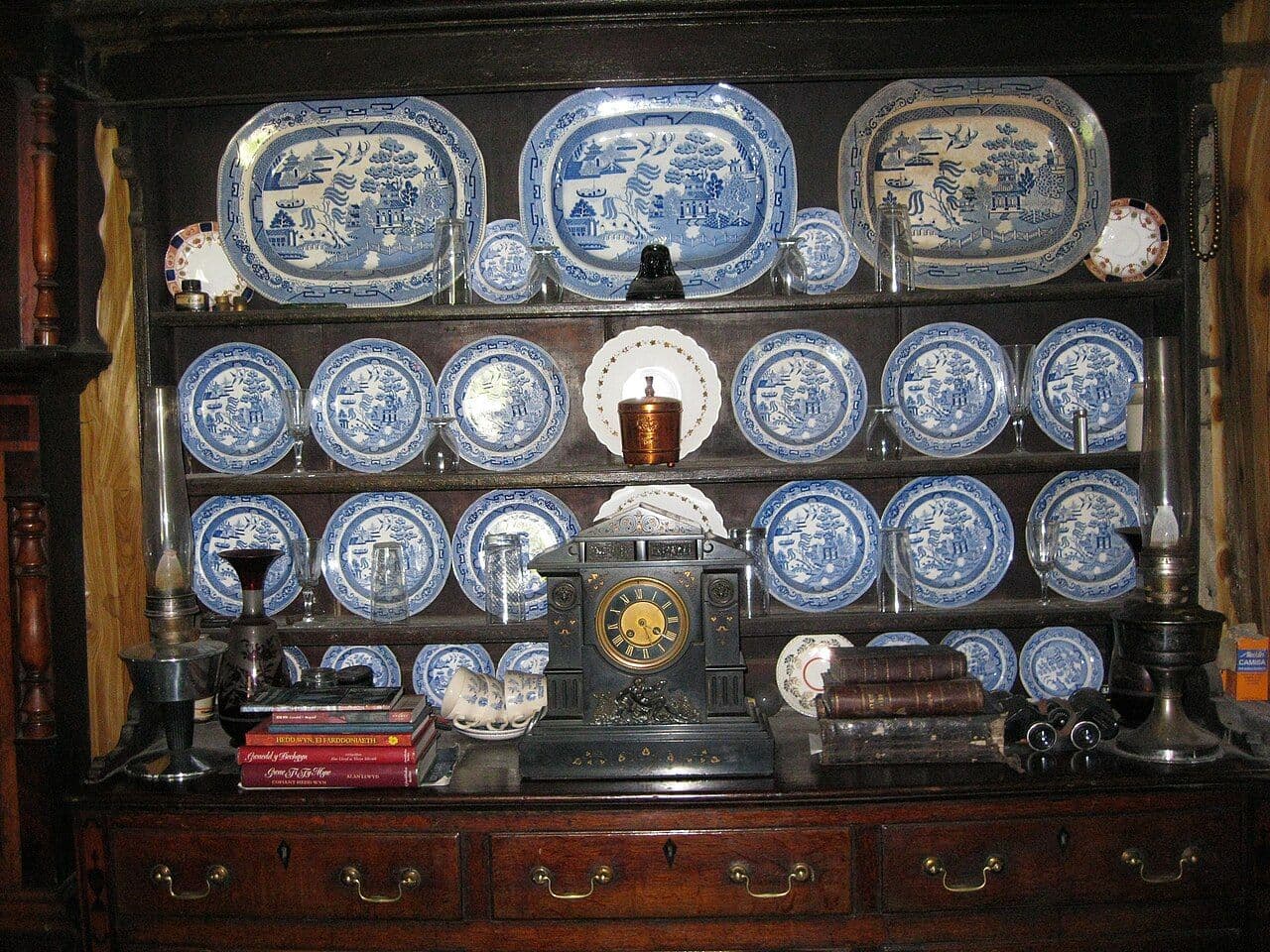 Dark wood dresser filled with blue-and-white plates and a mantel clock