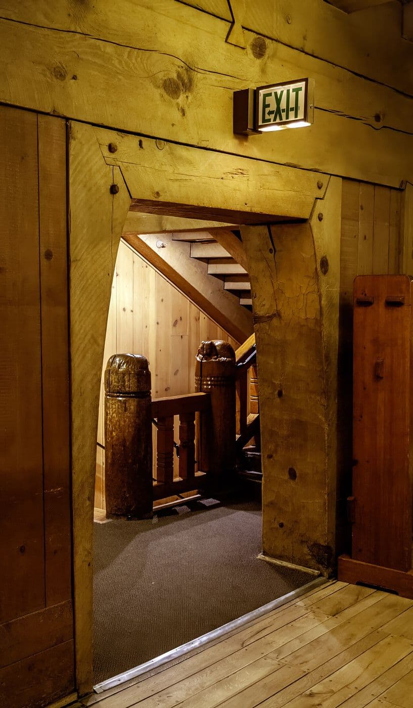 Doorway framed with thick timber posts and a heavy lintel leading to a stair
