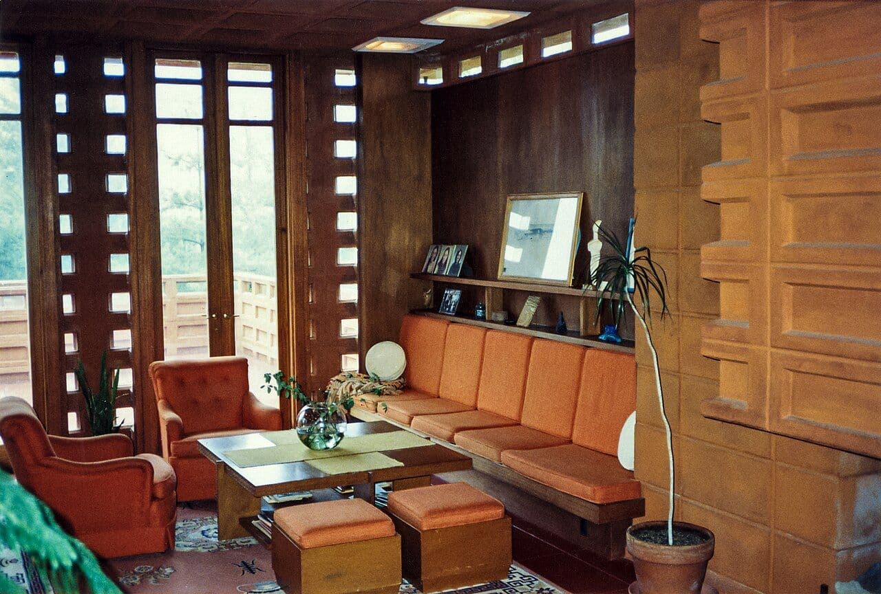 Mid-century living area with a long built-in sofa, wood paneling and patterned block walls