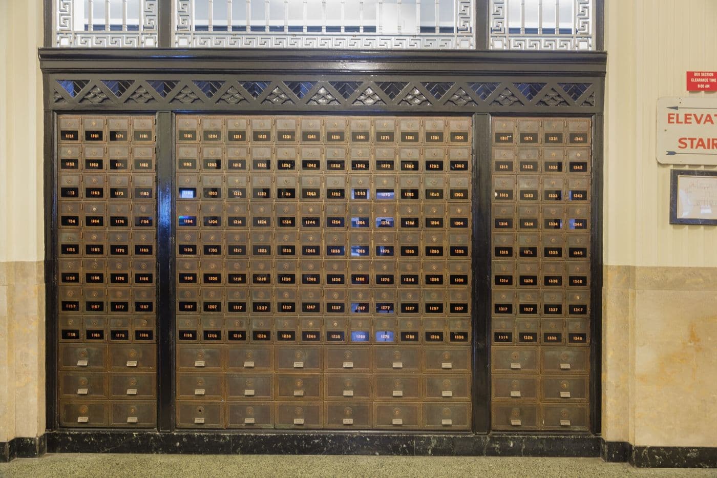 Wall of small metal Art Deco post office box doors in a decorative frame