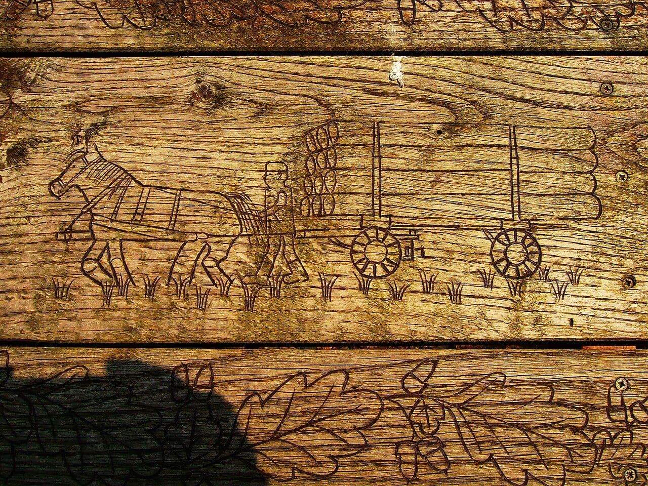 Wooden bench back carved with a scene of horses hauling logs