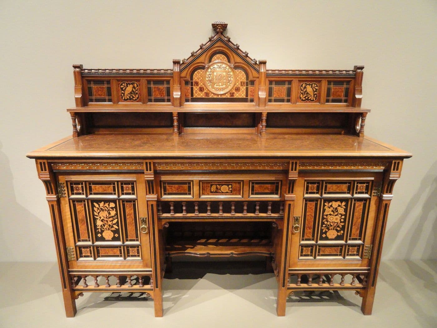Walnut cabinet with inlaid geometric door panels, turned colonnettes and an open center section