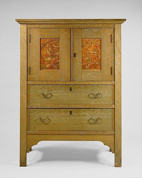 Oak linen press with decorative door panels above drawers and brass hardware