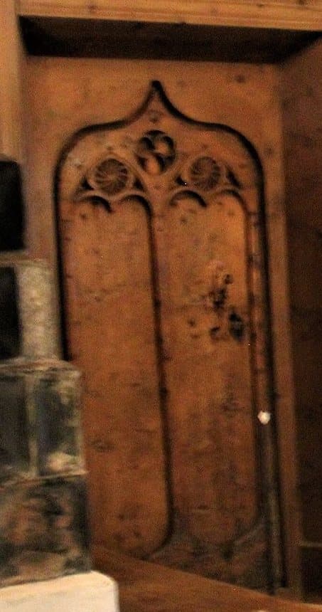 A pine board door in a Tyrolean Stube carved with a tall ogee-arched Gothic frame and three rosettes in the arch