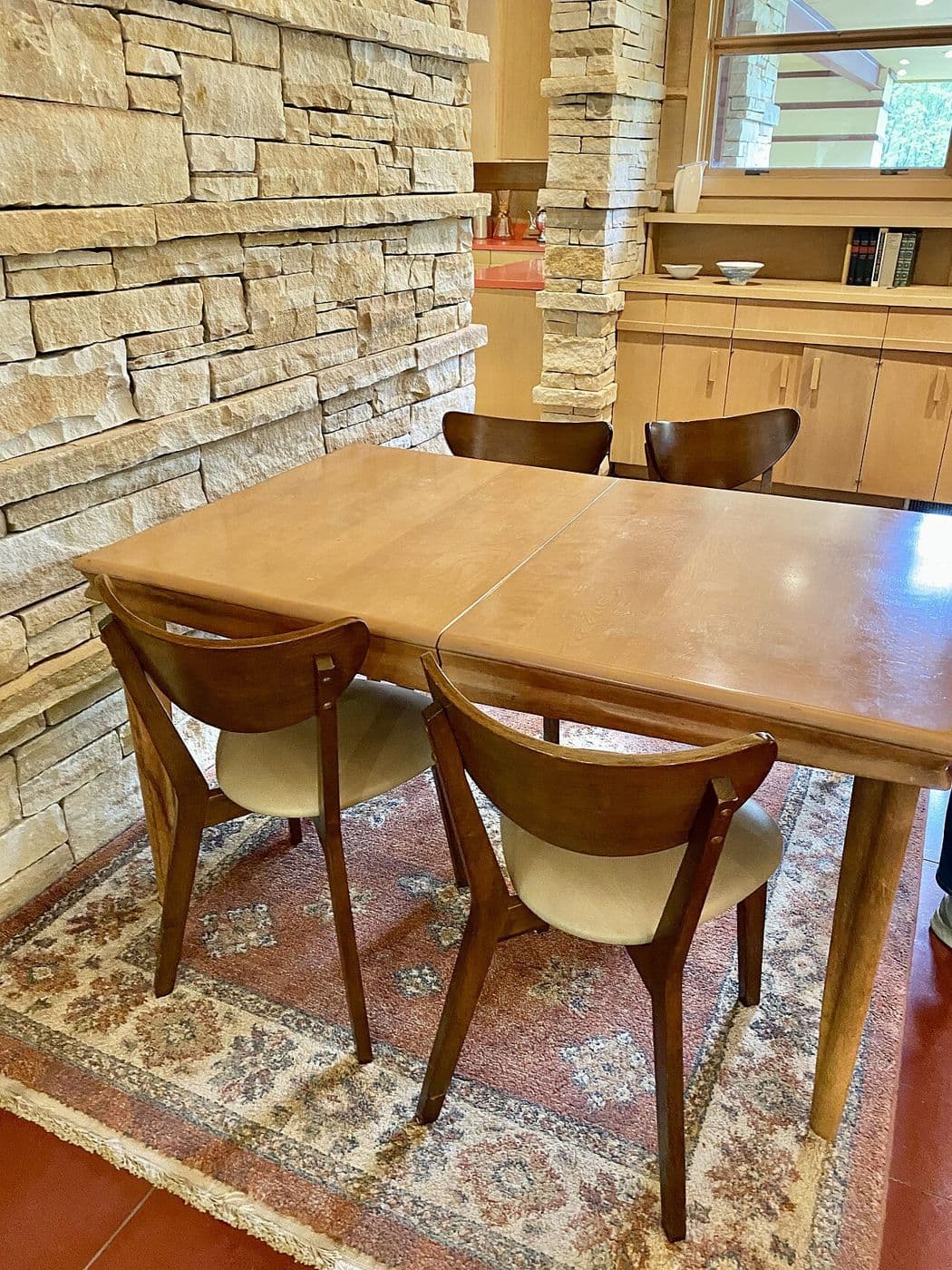Mid-century dining area with a stacked stone wall, built-in wood cabinets and a dining table