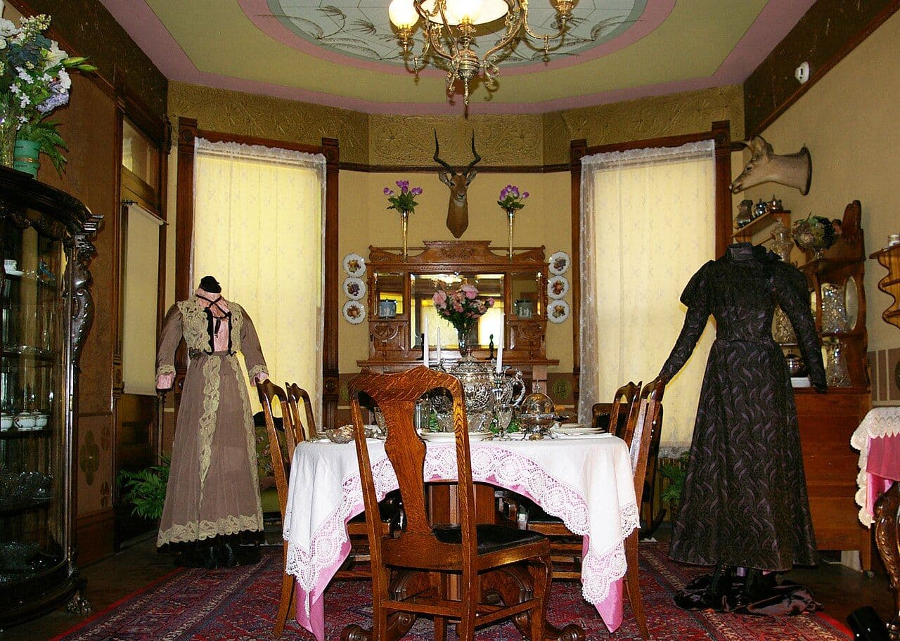 Victorian dining room with built-in mirrored sideboard, glazed china cabinet and period costumes