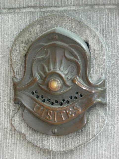 Art Nouveau metal door fitting with flowing curves on a stone wall