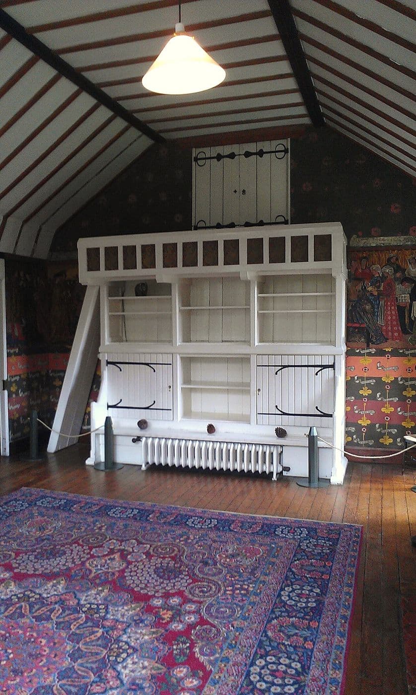 Drawing room at Red House with a large painted built-in settle and cupboard and a brick fireplace