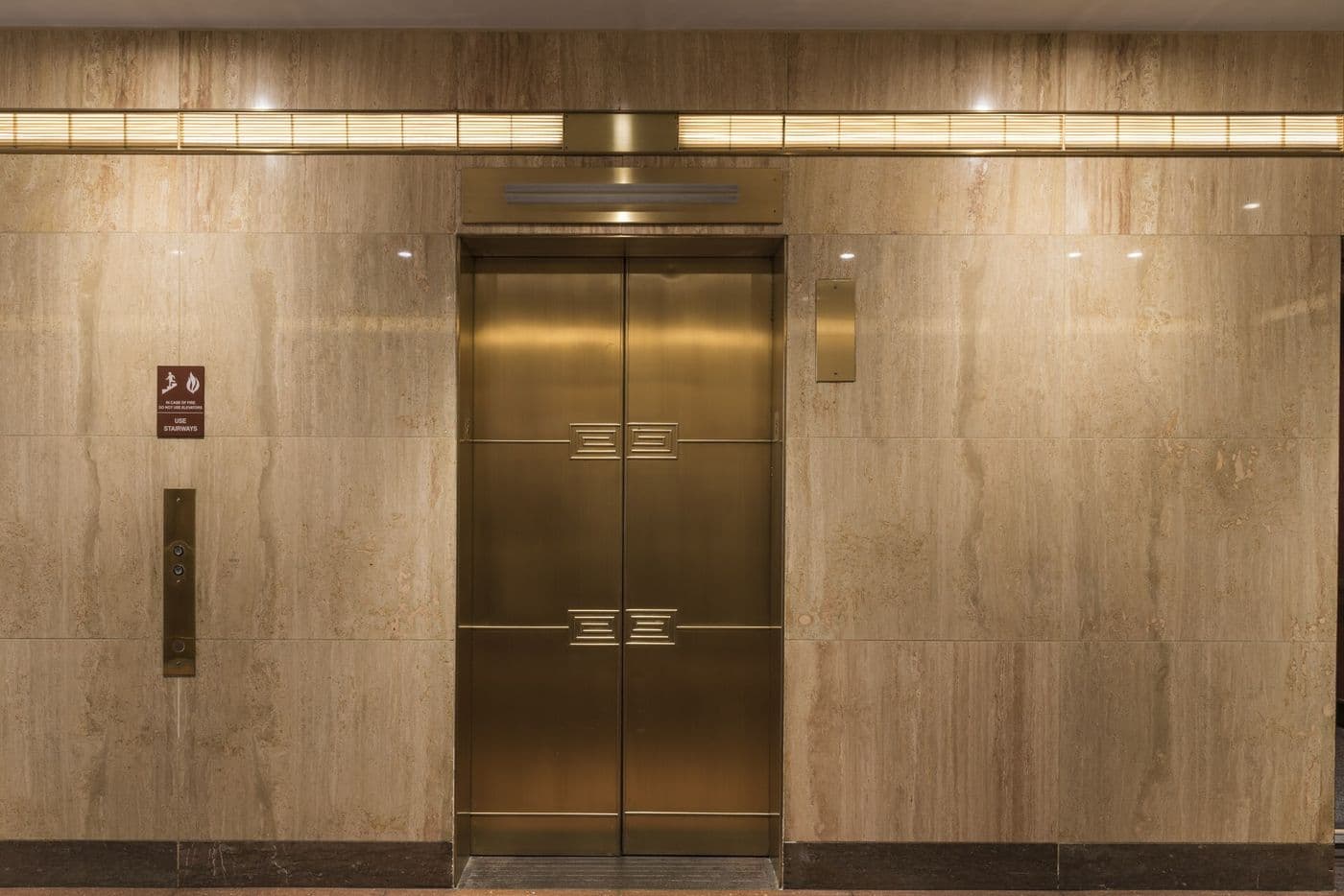 Decorated metal elevator door with a geometric pattern in a building lobby