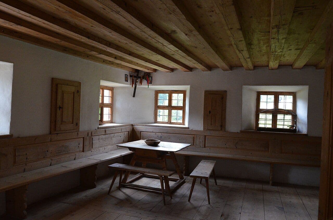 Tyrolean farmhouse room with a built-in corner bench, wood-paneled walls and a tiled stove