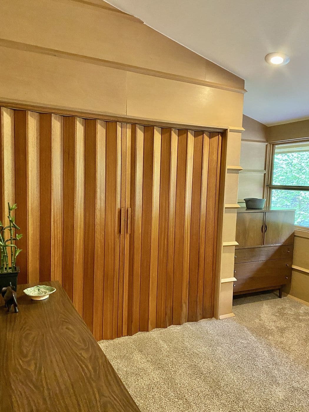 Folding wood accordion partition in vertical panels in a mid-century room