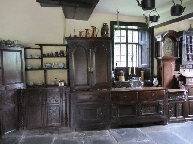 Dark farmhouse kitchen with carved oak built-in cupboards and open shelves