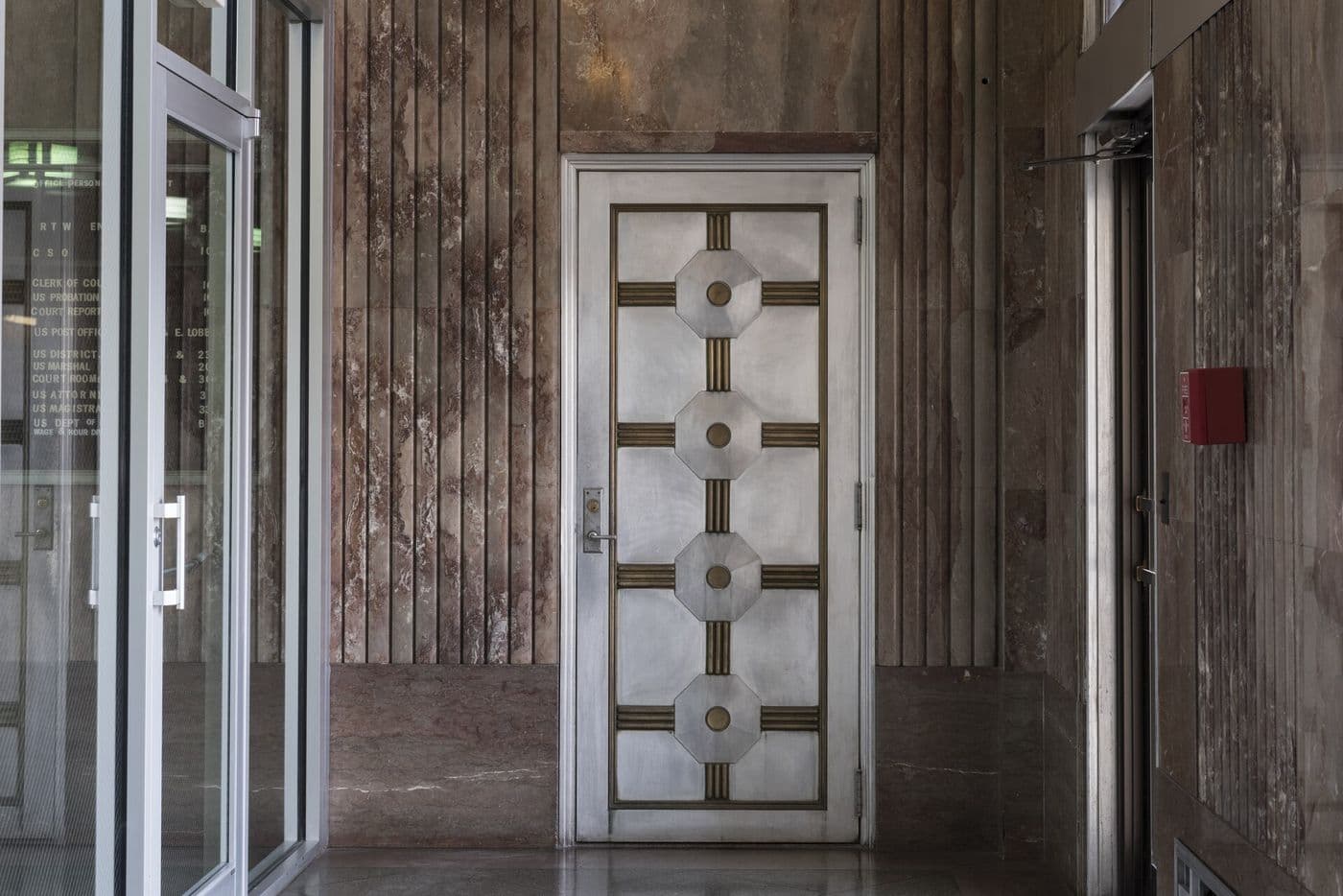 Art Deco lobby door with geometric metal panels and a transom