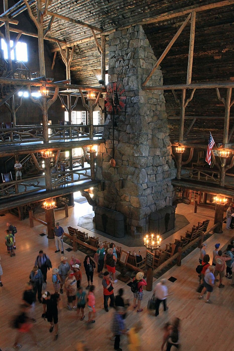 Old Faithful Inn lobby with a huge stone chimney and tiers of log balconies