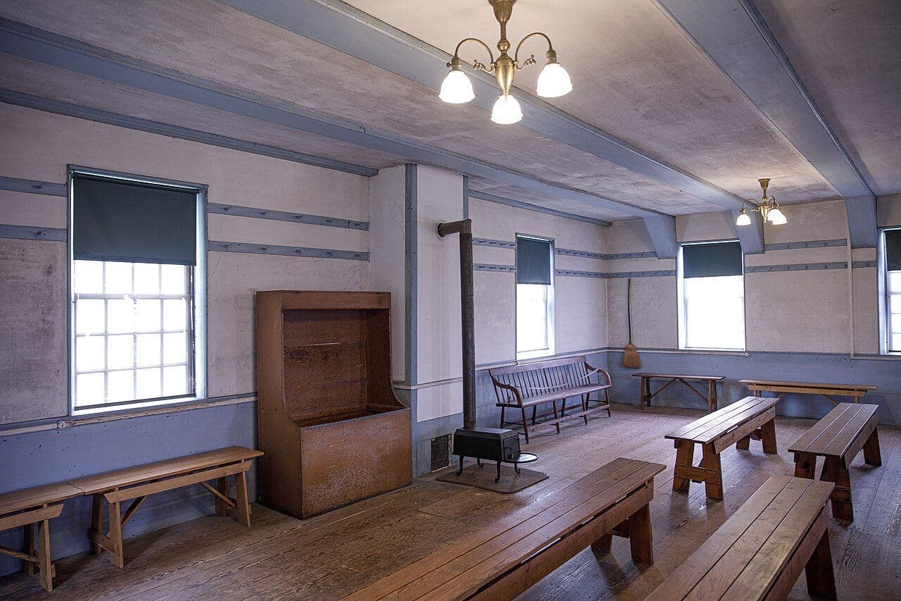 Shaker meeting house interior with painted blue woodwork, built-in cupboard and wooden benches