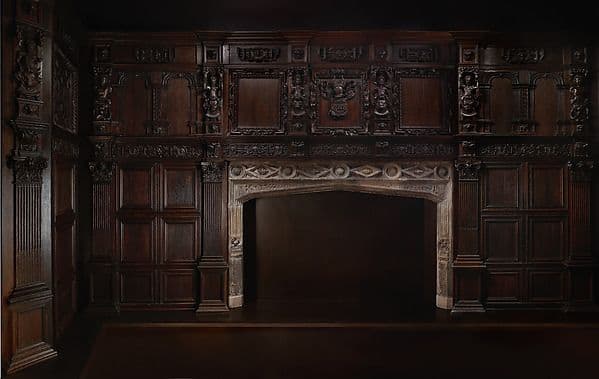 Room of dark oak small-panel paneling with a carved frieze and chimneypiece