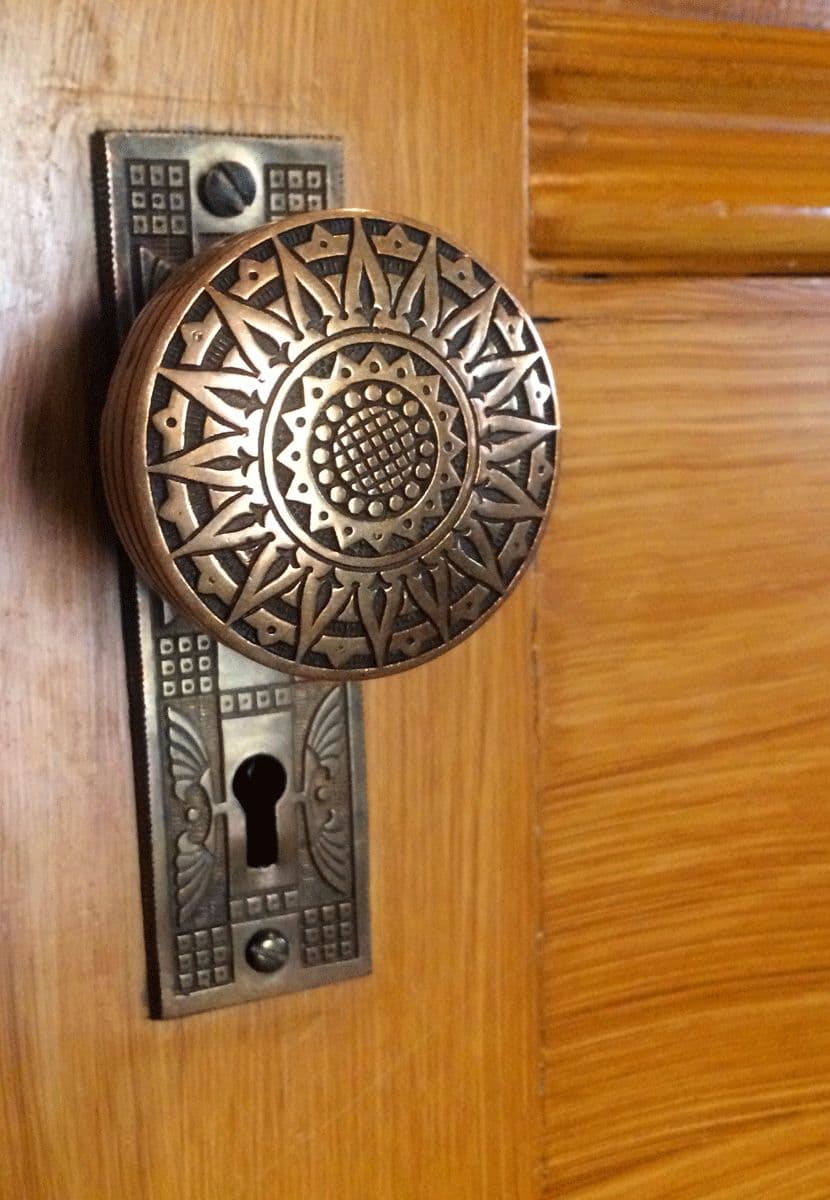 Close-up of an ornate patterned doorknob and rosette on a wooden door at the Molly Brown House