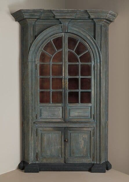 Tall painted corner cupboard with arched glazed upper section and paneled lower doors
