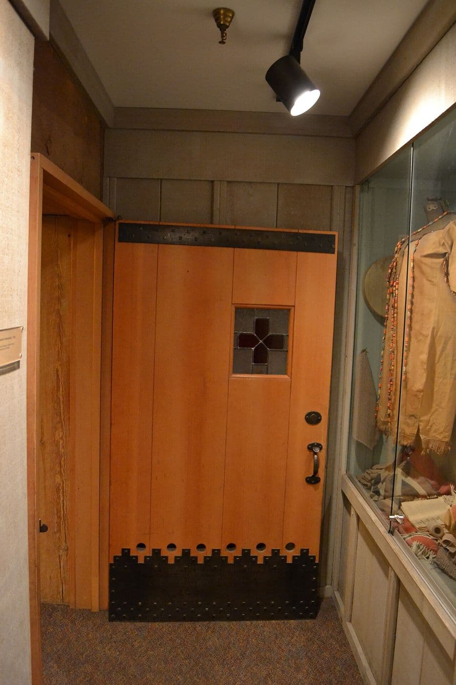 Wooden plank door with a small window and decorative iron strapwork at the base