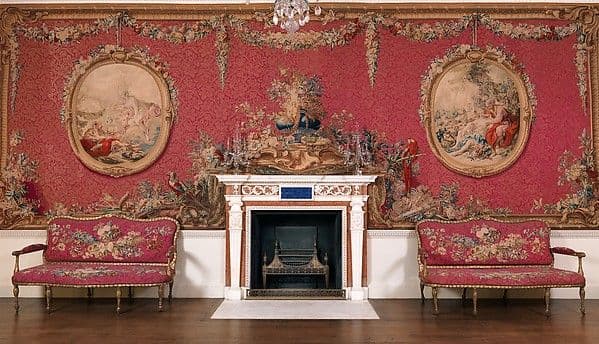 Neoclassical room with tapestry-covered walls framed by gilded mouldings and an ornate ceiling