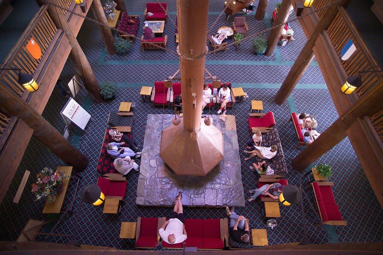 Hotel lobby seen from above with a central fireplace and a large suspended metal hood