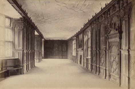 Historic photograph of the oak-paneled Long Gallery at Haddon Hall with tall windows