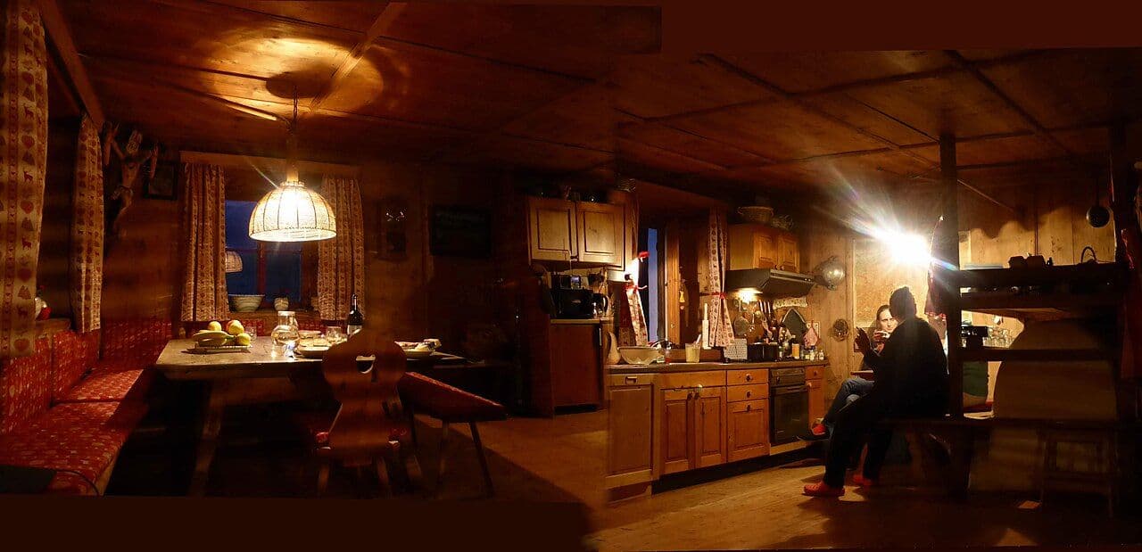 Panoramic photograph of a Tyrolean wood-paneled farmhouse room with built-in seating