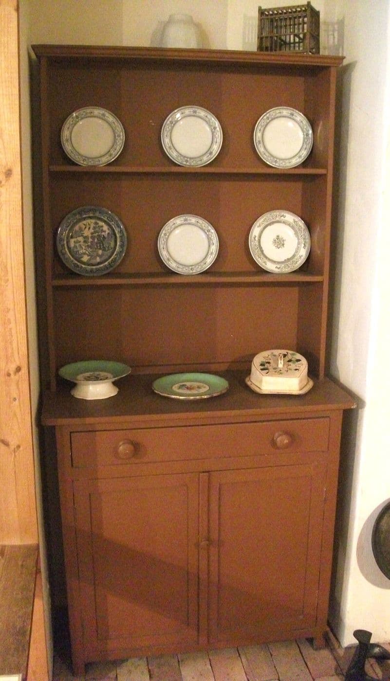 Wooden Welsh dresser with plates on open shelves above a two-door cupboard